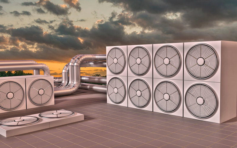 Rooftop HVAC system with multiple industrial units and ductwork silhouetted against dramatic sunset sky.
