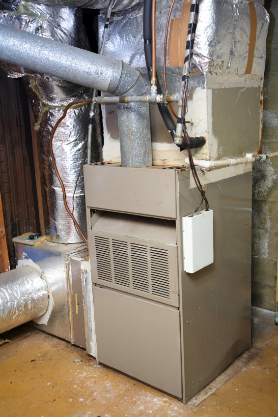 Vertical forced-air furnace with vented front panel, insulated ductwork, and side-mounted control box in utility room.