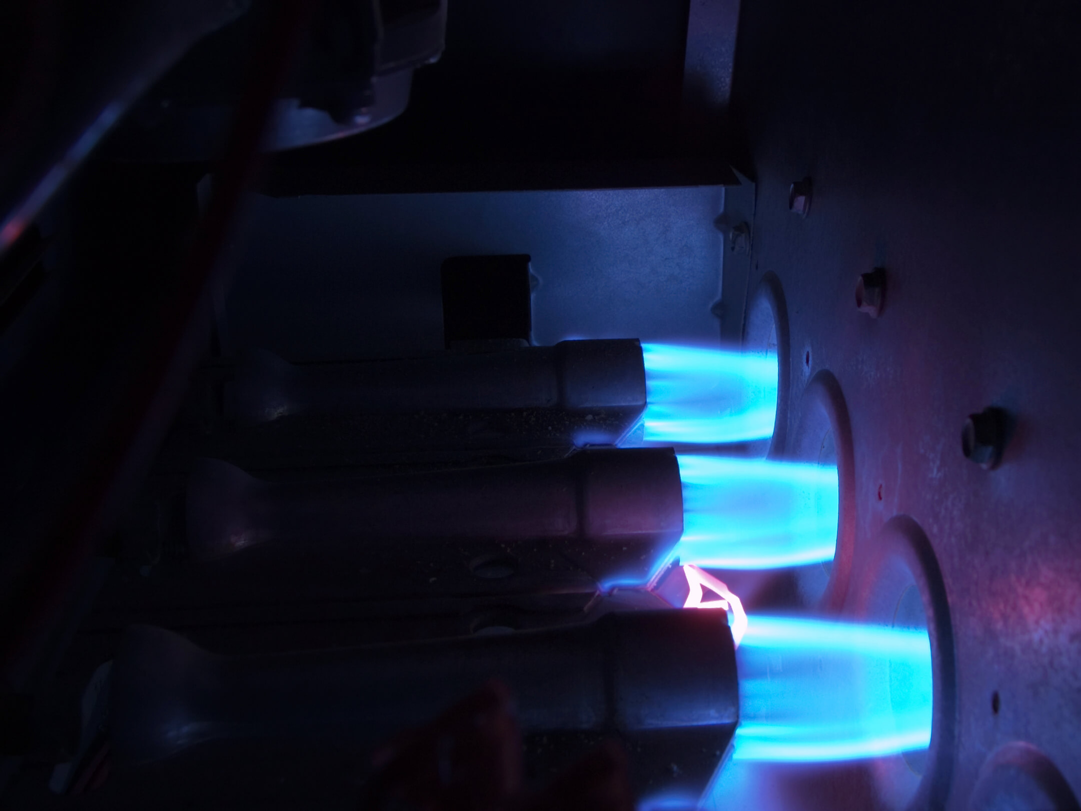 Interior view of gas furnace burner assembly with steady blue flames indicating efficient combustion.