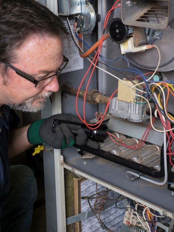 A technician is working on a gas furnace.