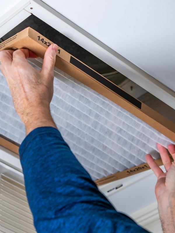 An HVAC technician replacing an air filter.