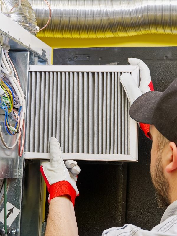 An HVAC Technician replacing an HVAC filter for a unit.