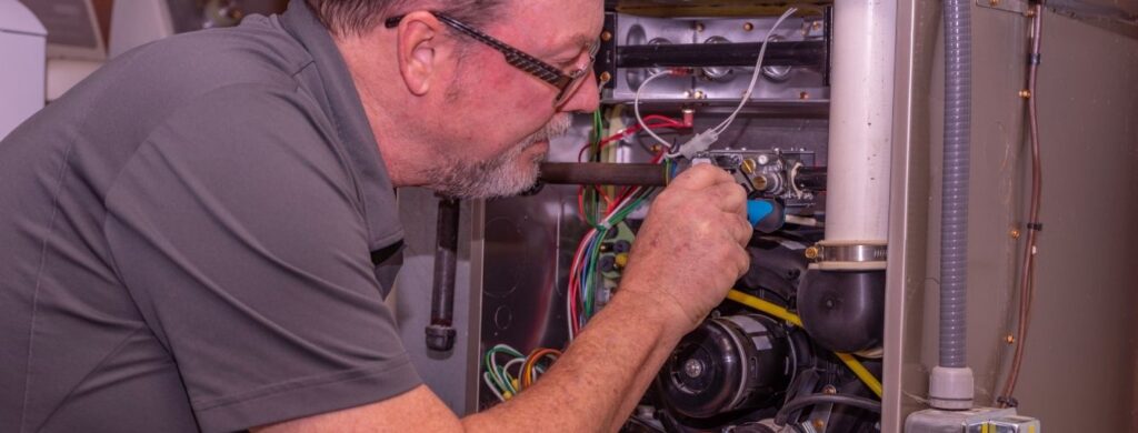 An HVAC technician is working on a furnace. 