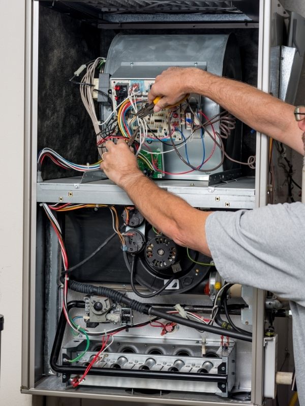 An HVAC technician is working on a heater. 