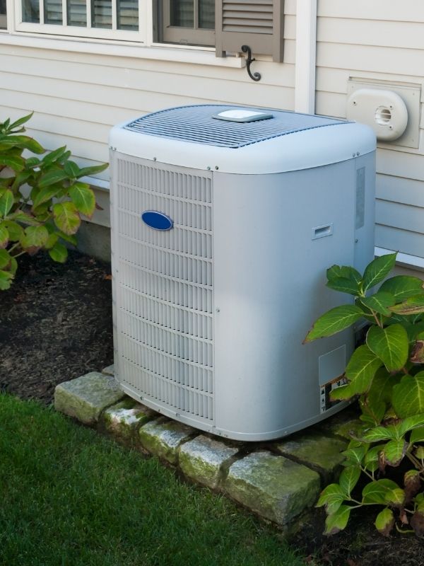 An air conditioner outside of a house. 