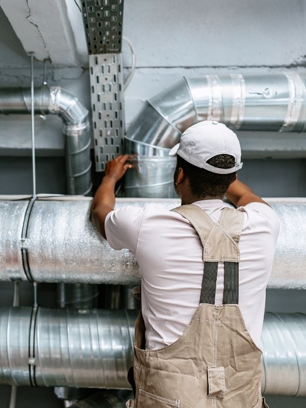 An HVAC technician checking commercial ductwork.